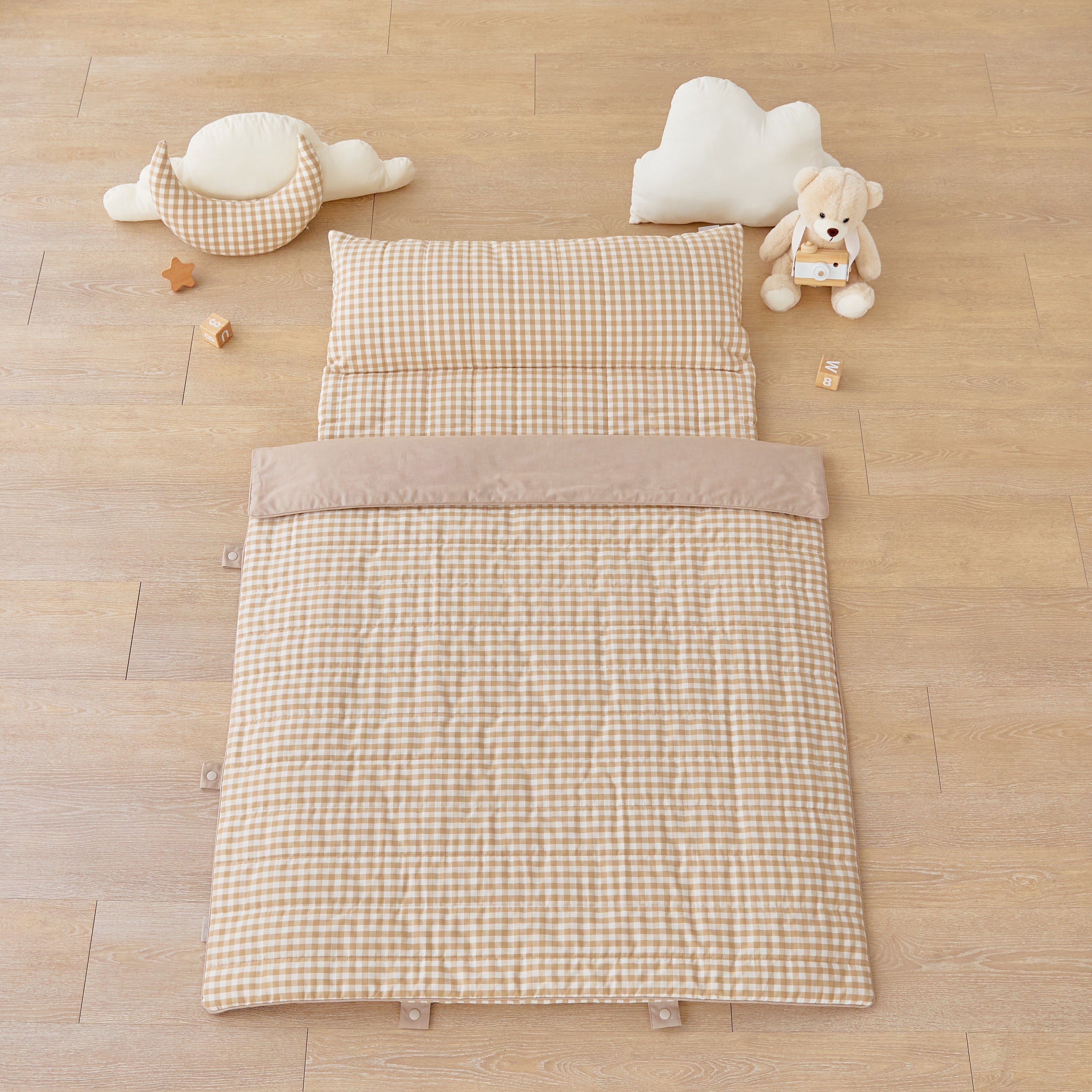 kid's day care nap mat blanket on wooden floor in brown tan beige checkered pattern