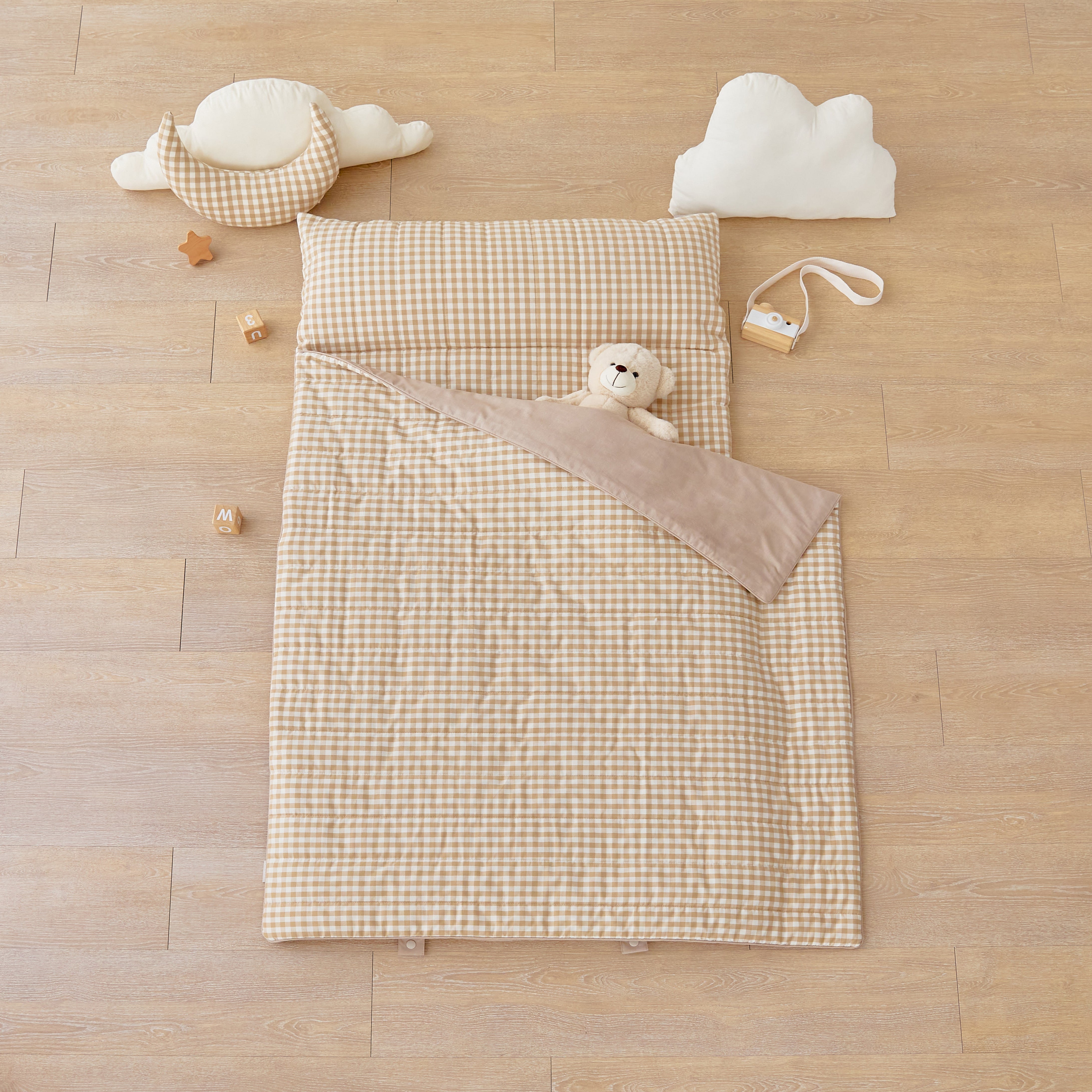 kid's nap mat blanket on wooden floor in brown tan beige checkered pattern