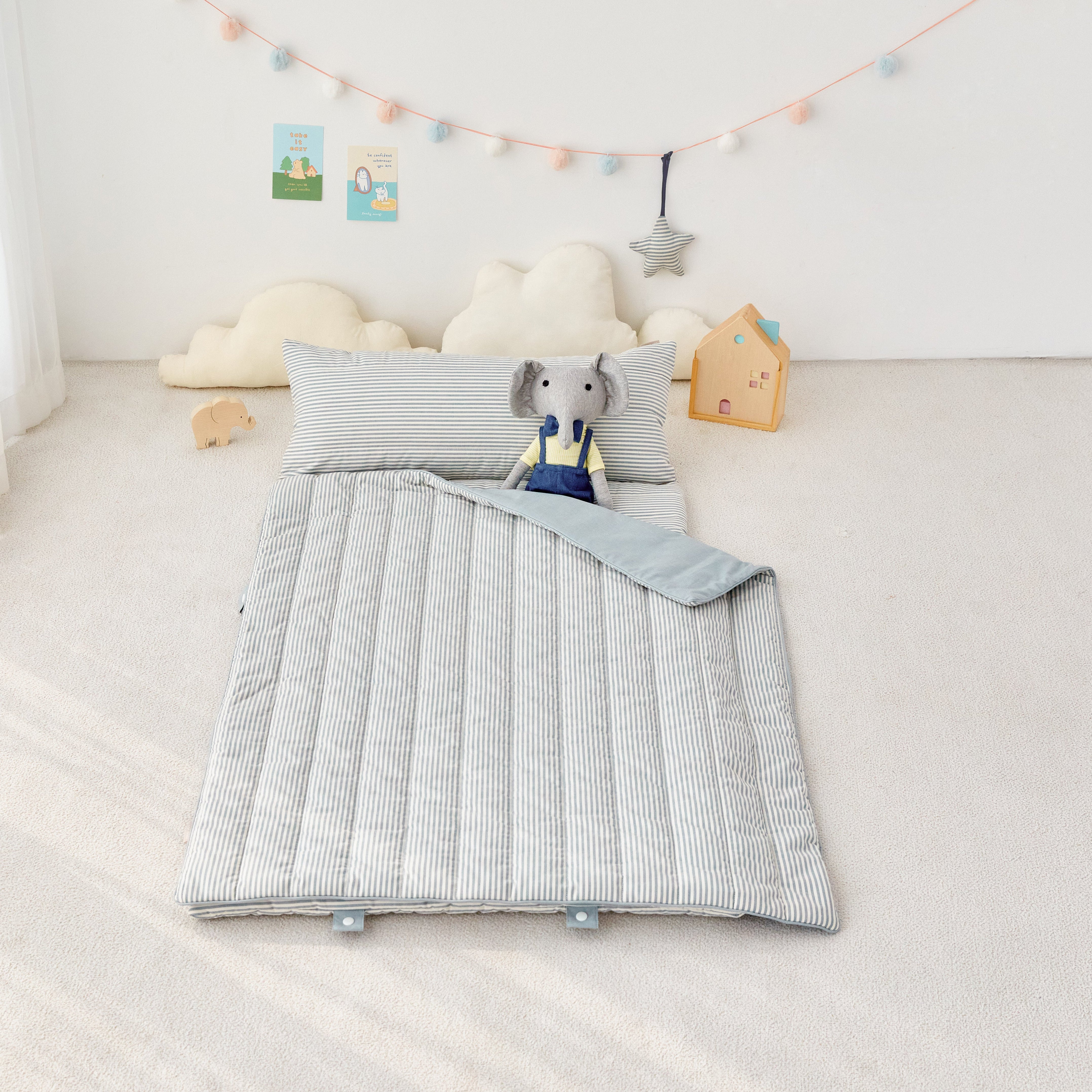 Children's room with a potable striped nap mat blanket and pillow featuring an elephant toy.