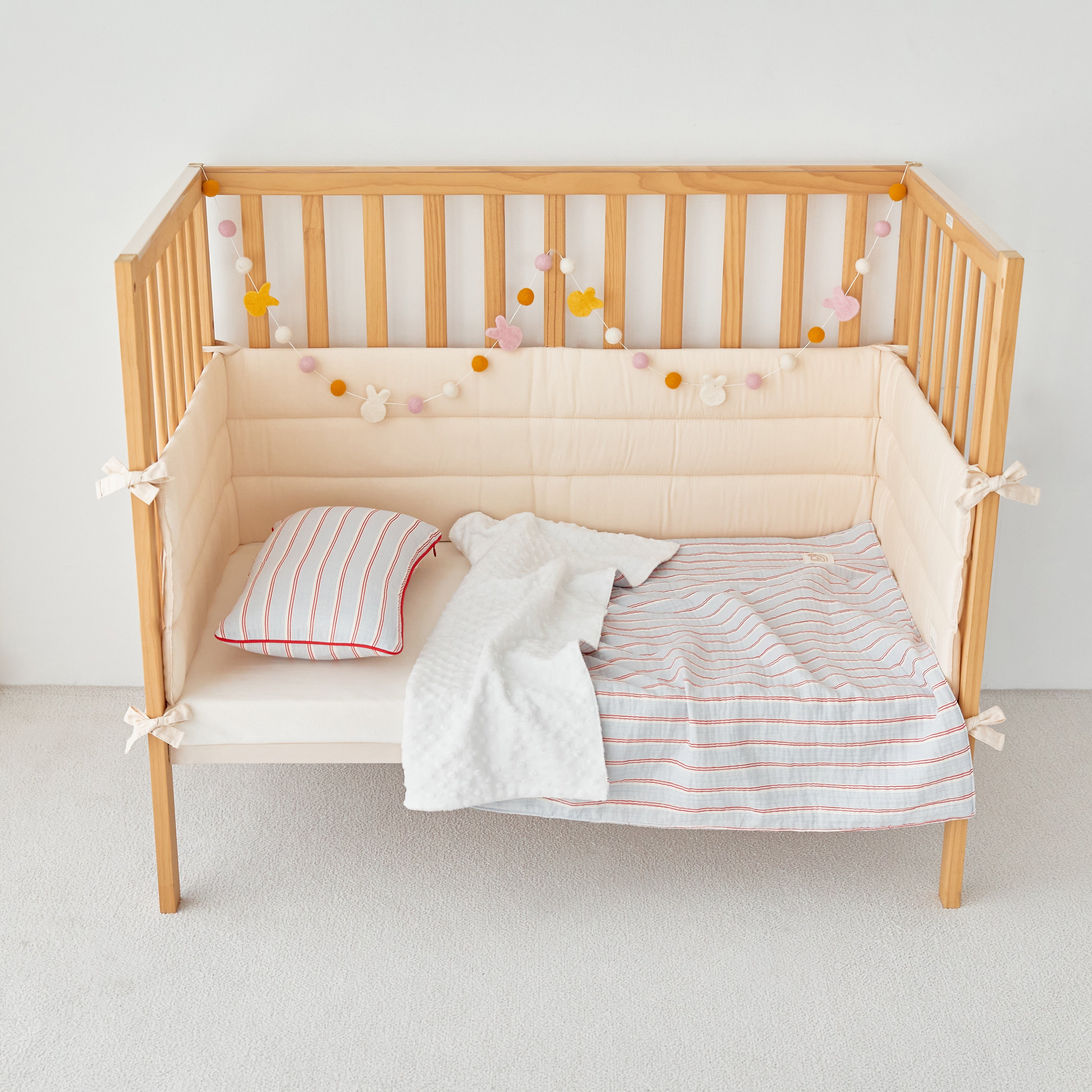Wooden crib with baby boy blue crib blanket and pillows on a white background