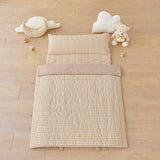 kid's day care nap mat blanket on wooden floor in brown tan beige checkered pattern