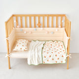 Wooden crib with cherry print baby bedding on a white background
