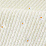Close-up of a textured white kids nap mat blanket with embroidered daisies 