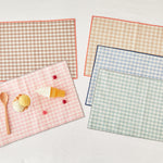 Set of kids checkered placemats with a small dessert on a light background