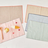 Set of kids checkered placemats with a small dessert on a light background