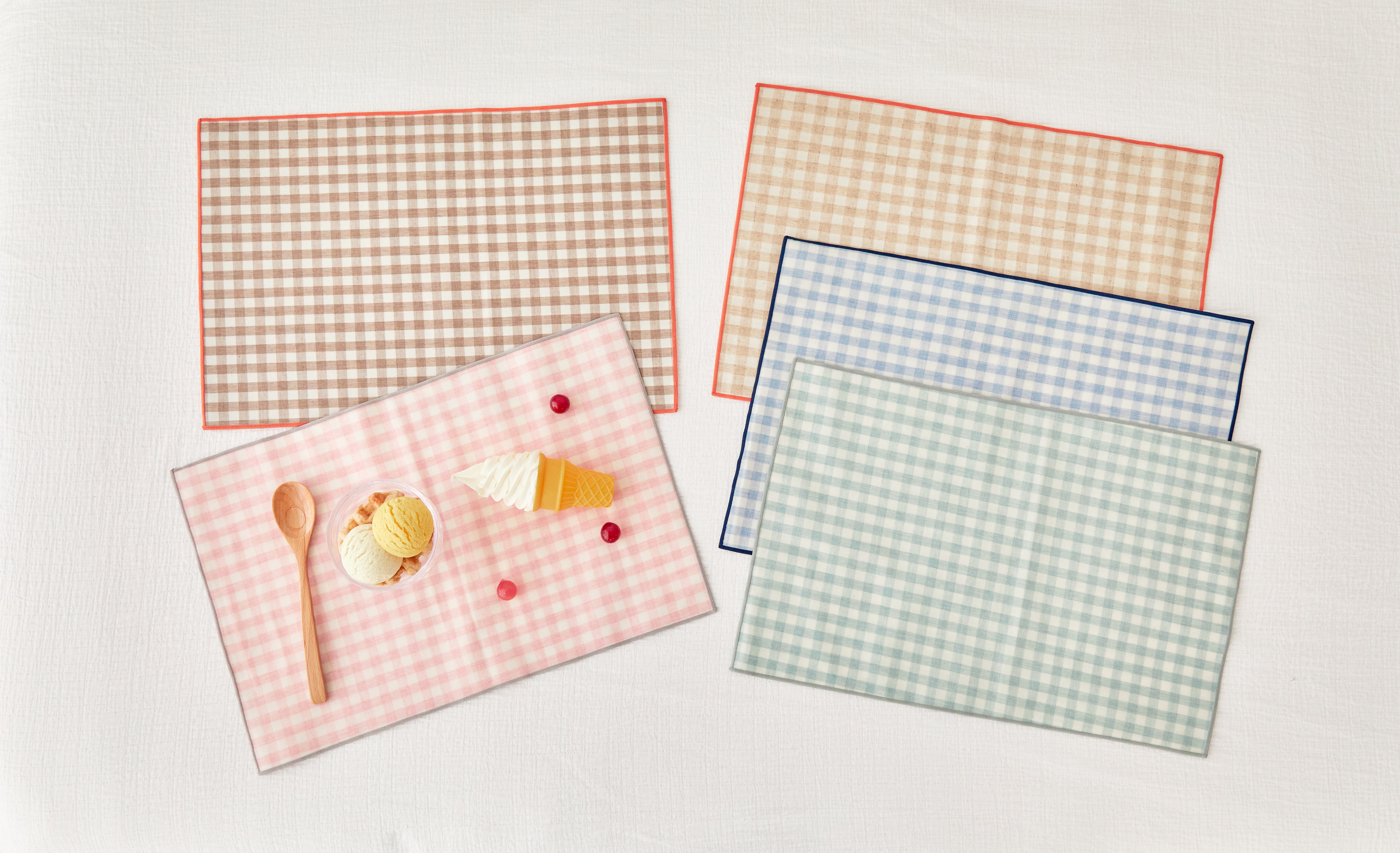 Set of kids checkered placemats with a small dessert on a light background