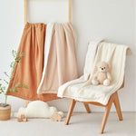 Ivory beige burnt orange gauze sherpa baby blankets draped over a chair