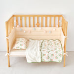 Wooden crib with strawberry print knitted cotton and minky baby blanket including a white blanket and green crib sheet with patterns on a plain background