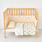 Wooden crib with strawberry print knitted cotton and minky baby blanket including a white blanket and green crib sheet with patterns on a plain background