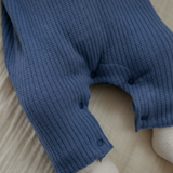 Close-up of a blue ribbed sweater on a beige surface