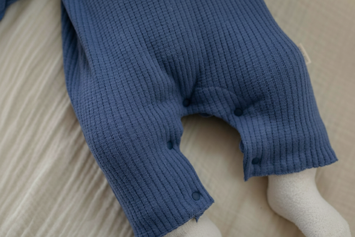 Close-up of a blue ribbed sweater on a beige surface