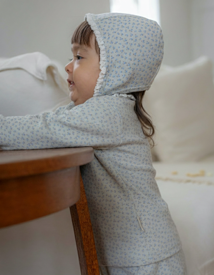 A toddler girl wearing a subtle blue floral patterned outfit.