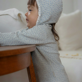 A toddler girl wearing a subtle blue floral patterned outfit.