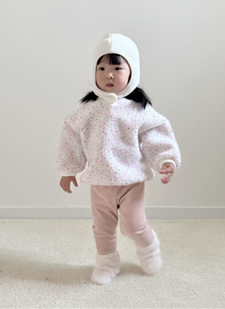 Child wearing a white hooded outfit with pink pants on a plain background