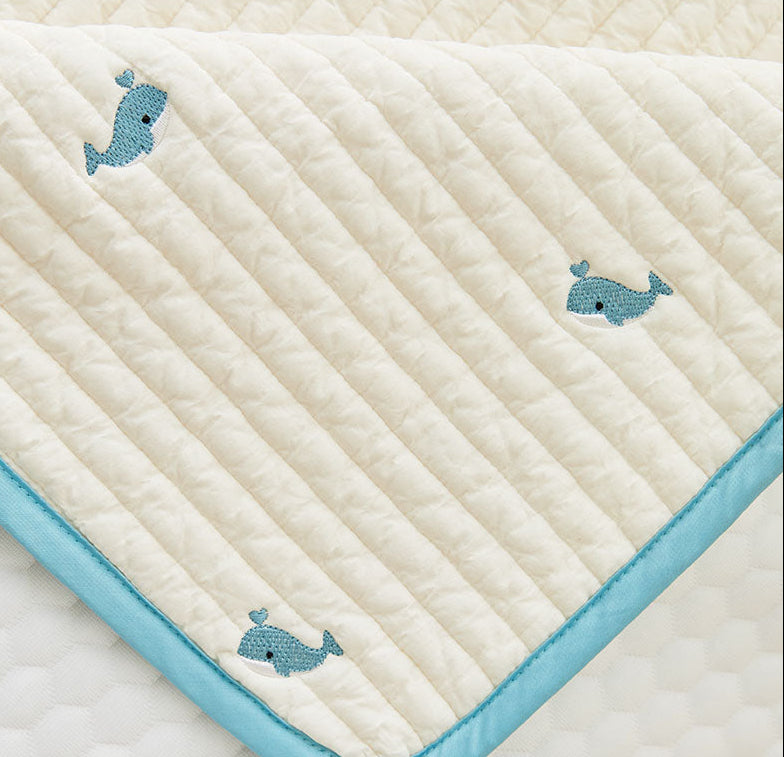 Quilted baby blanket with whale patterns on a textured surface
