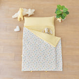 Baby portable nap mat blanket with yellow striped and blue pink bunny rabbit pattern on a wooden floor with toys and a plant.