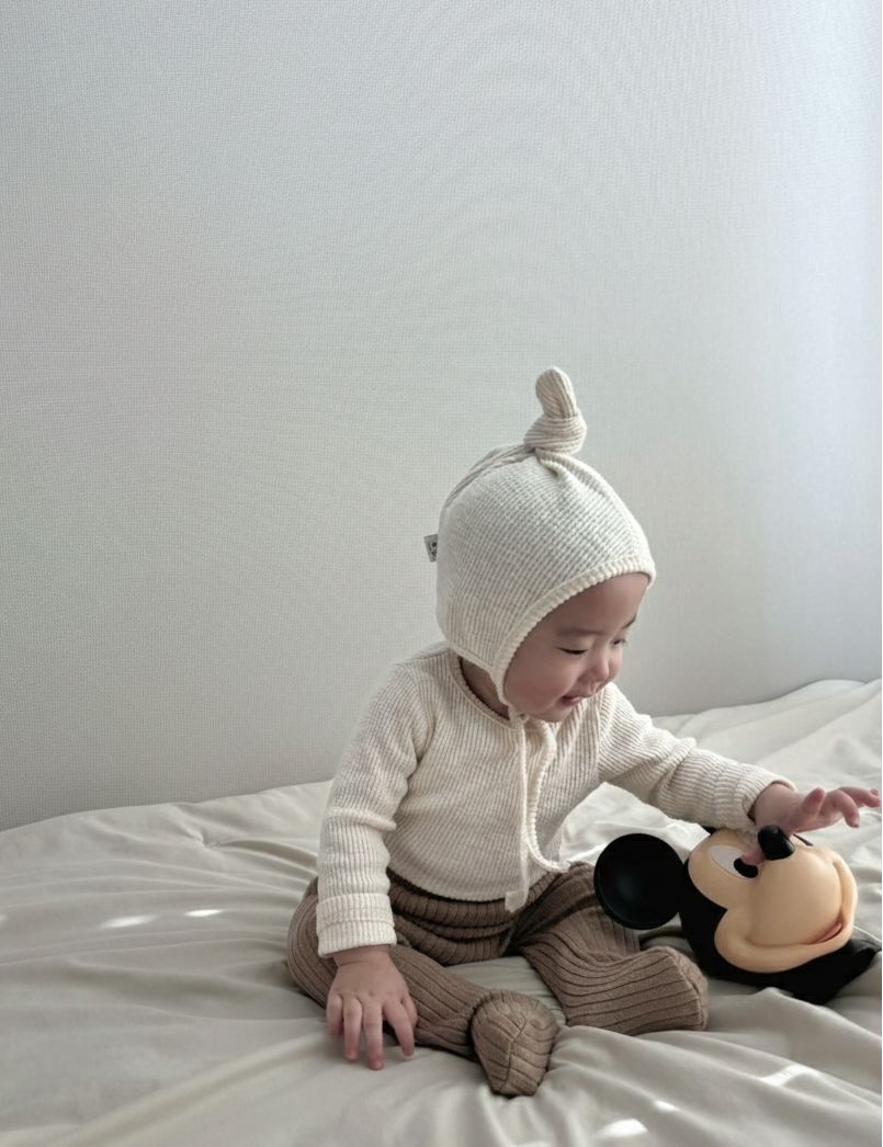 Baby wearing Cloud Soft Ivory Rib Knit Sweater styled with neutral leggings