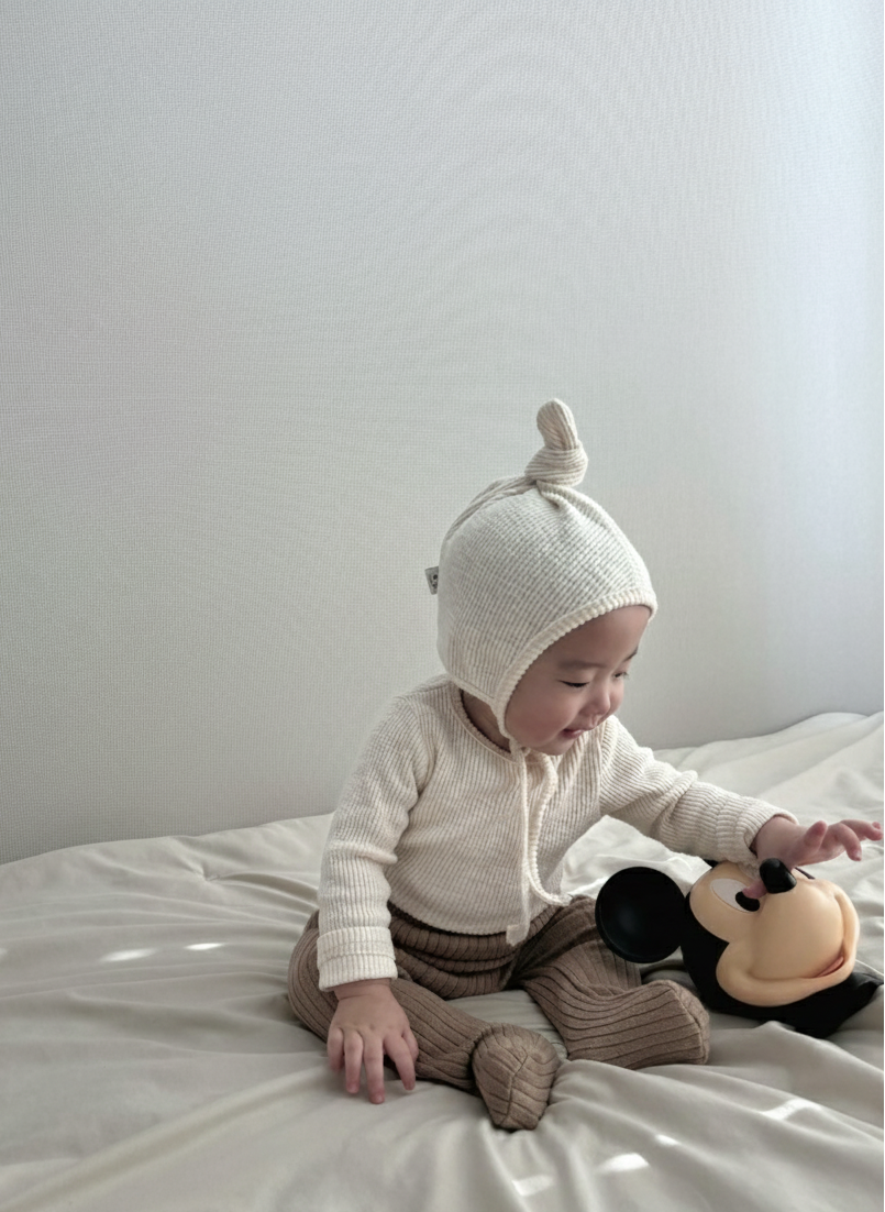 Baby wearing Cloud Soft Ivory Rib Knit Sweater styled with neutral leggings