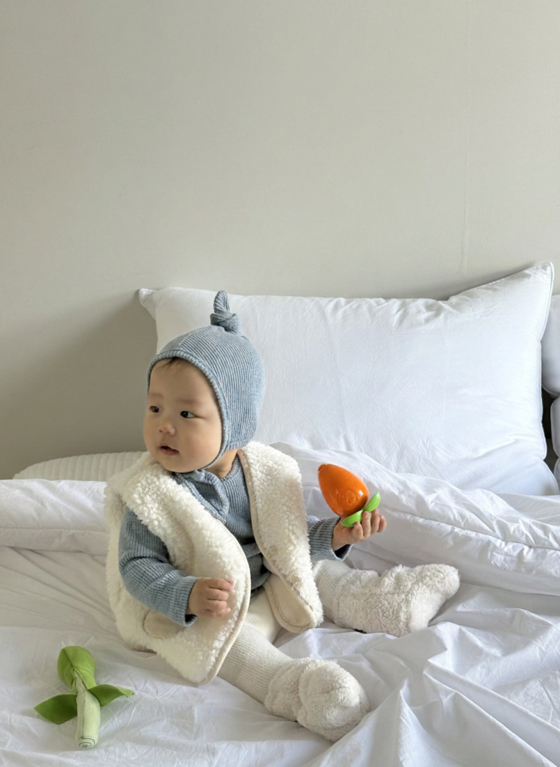 Baby wearing Cloud Soft Rib Knit Sweater styled with neutral leggings and dumble vest for cozy winter styling