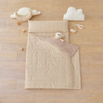 kid's nap mat blanket on wooden floor in brown tan beige checkered pattern