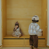 Neutral baby clothing flat lay with Cloud Dumble Sweater Soft Check and seasonal accessories