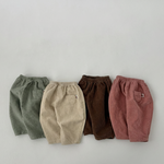 Four pairs of corduroy pants in green, beige, brown, and red on a light gray background.