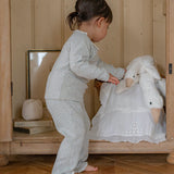 Child in pajama playing with a toy sheep in a goose in room.