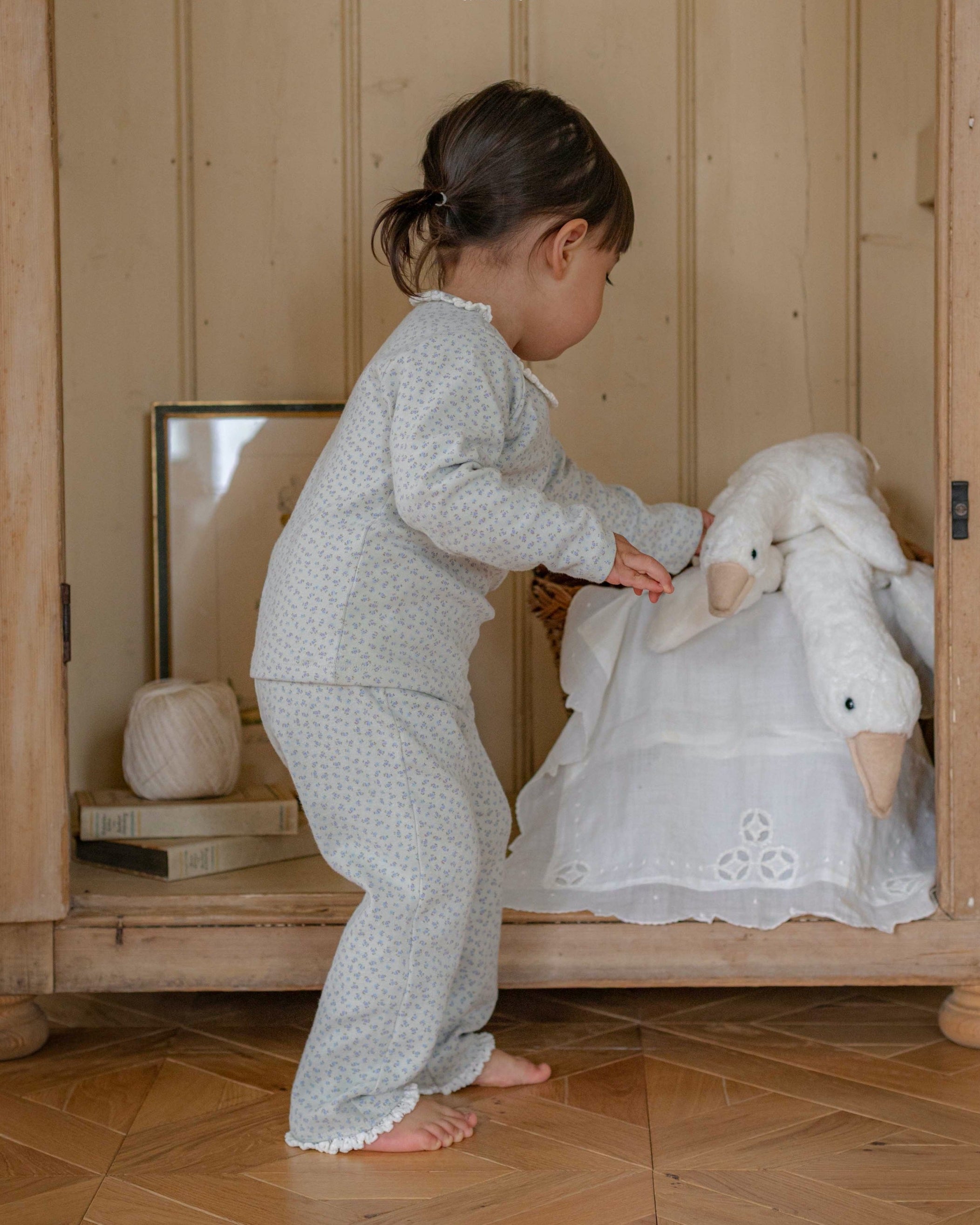 Child in pajama playing with a toy sheep in a goose in room.